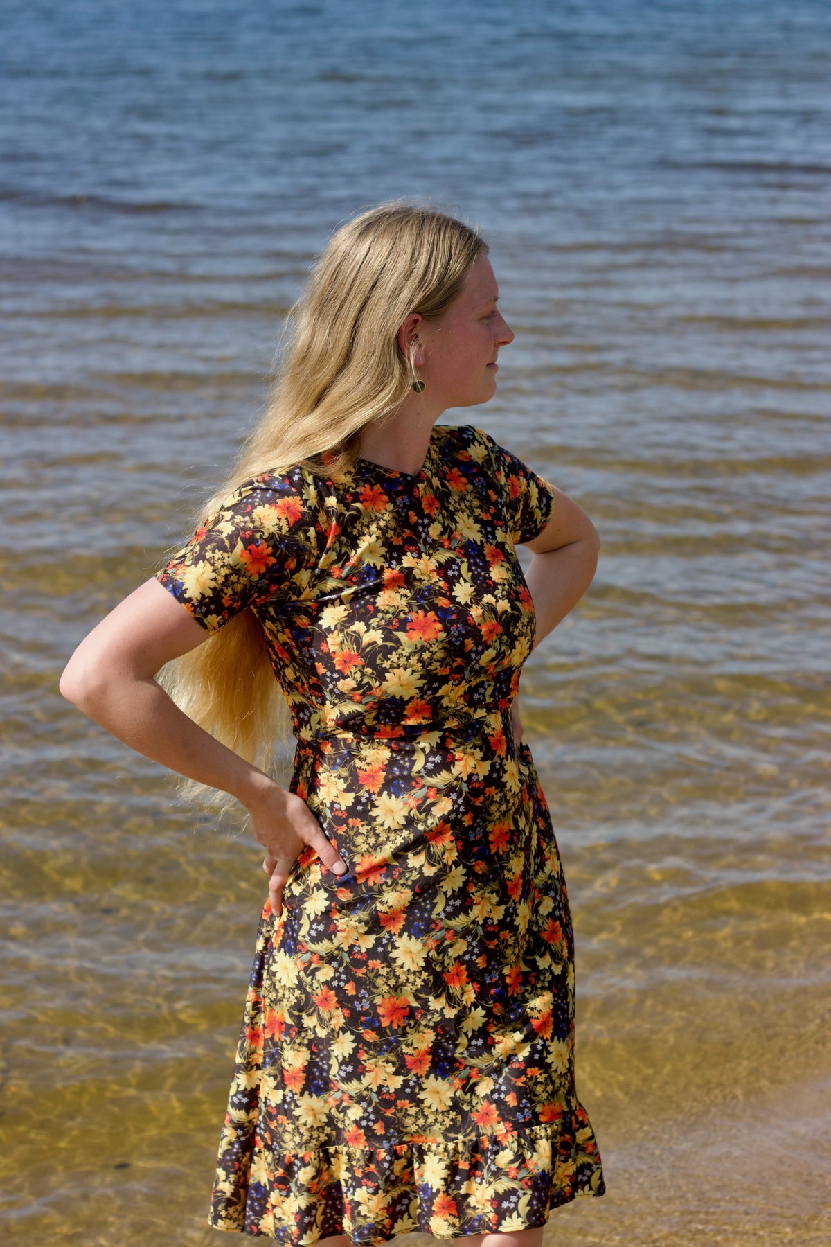 Woman in a floral dress standing by the water's edge